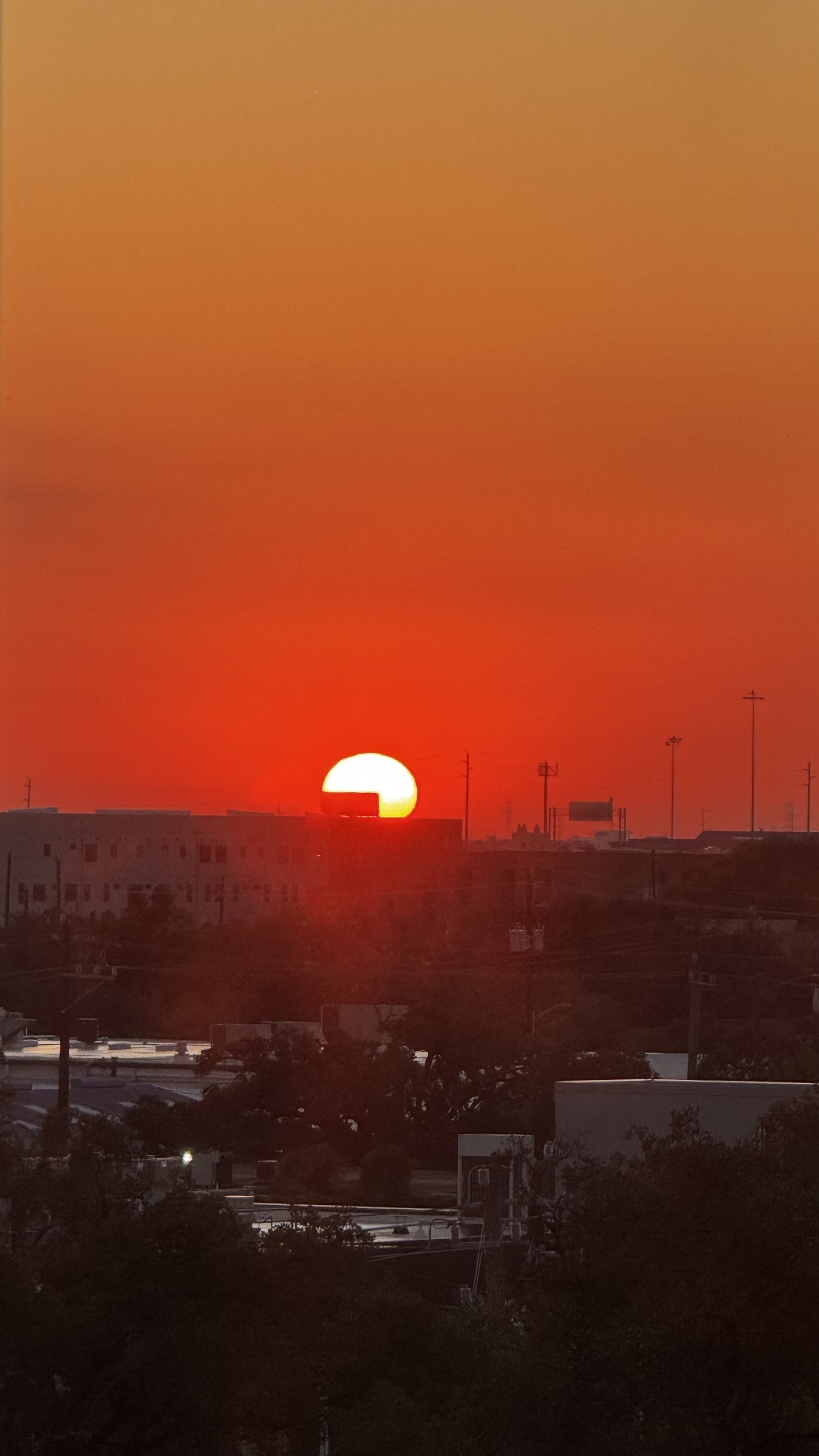 Sun rising on the horizon cover on the corner by a building 
