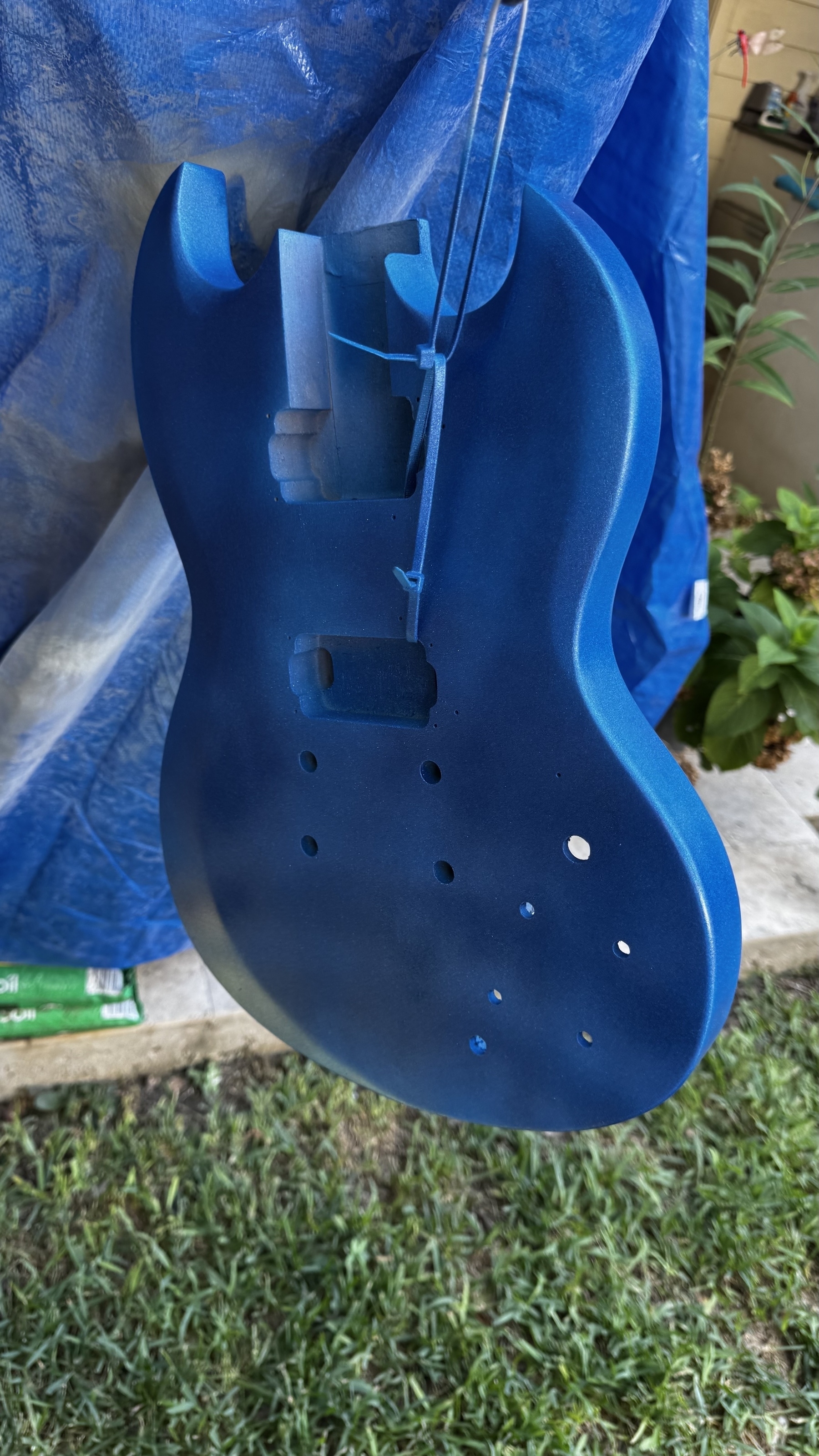 Guitar hanging and covered in blue sparkle paint. 