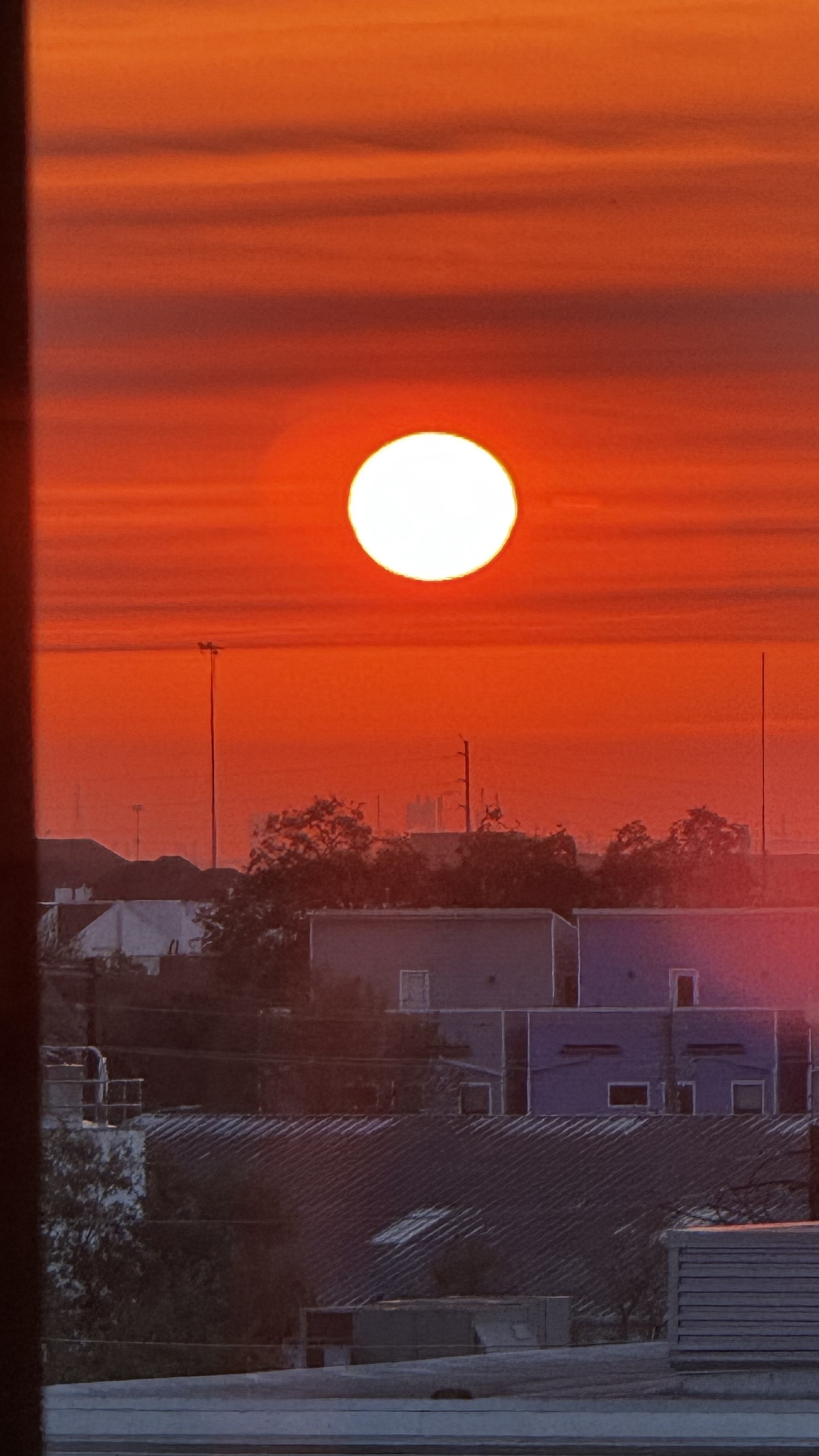 Sun, just over the horizon on a slightly cloudy morning. Houses in the fore ground